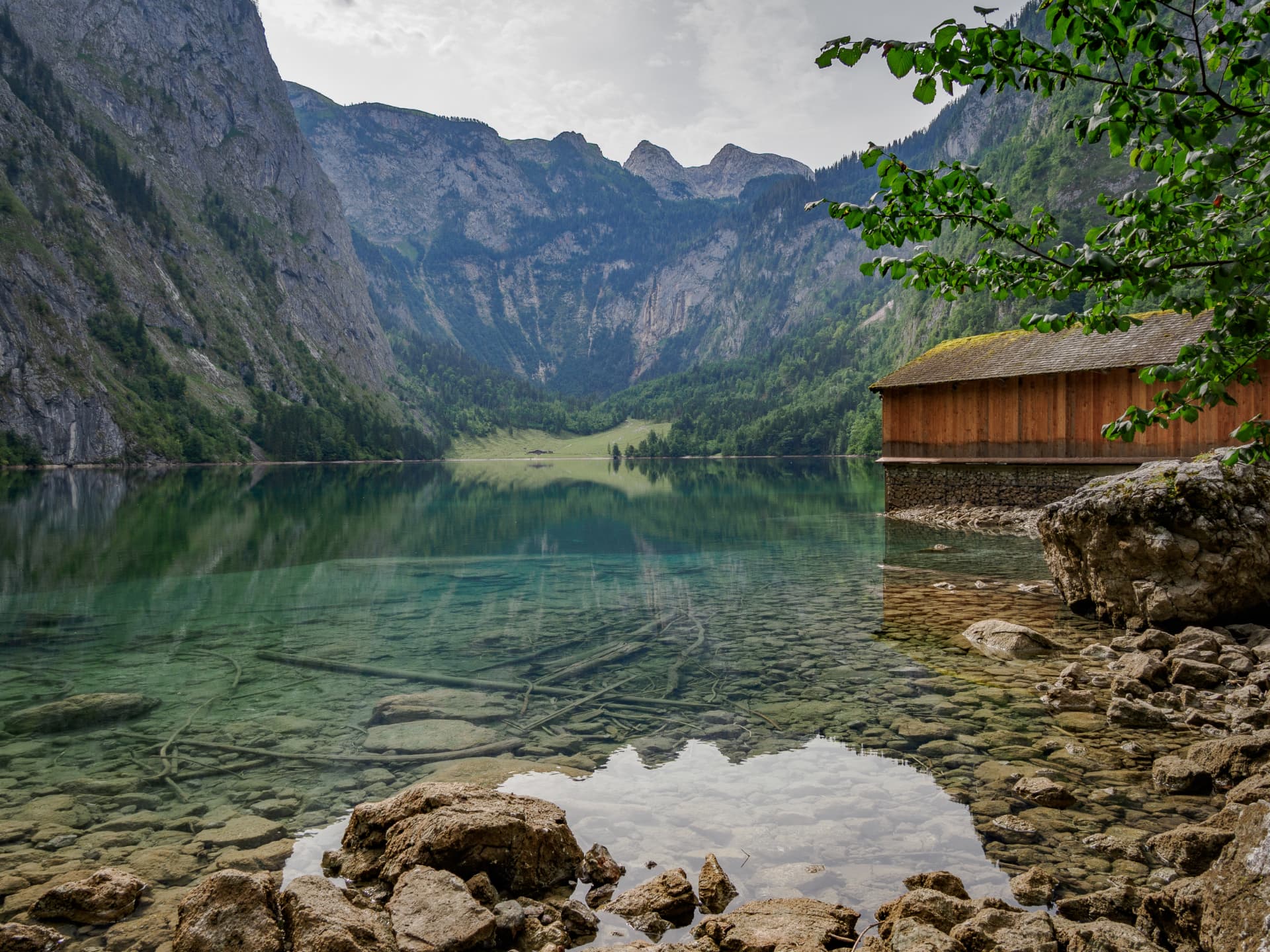 Boathouse at the clear waters of Obersee with forested mountains