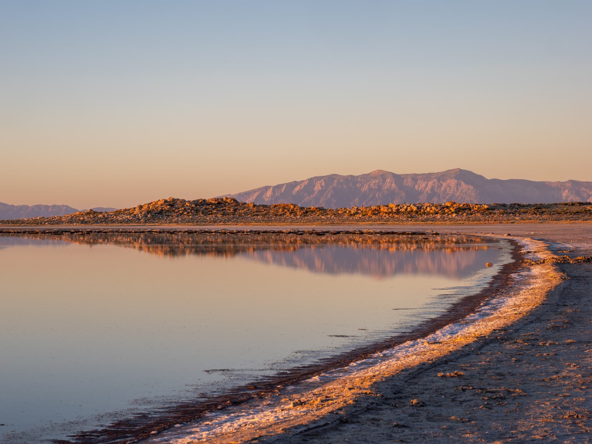 Salt shoreline reflecting mountains at first light