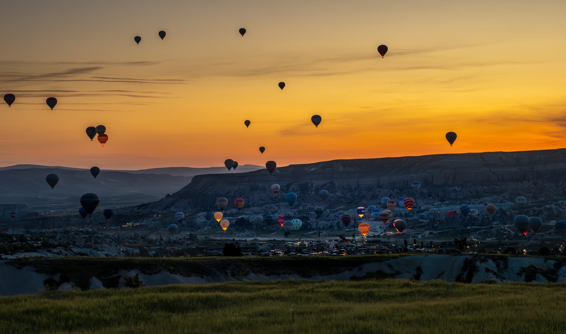 Dozens of hot air balloons drifting over Cappadocia at sunrise