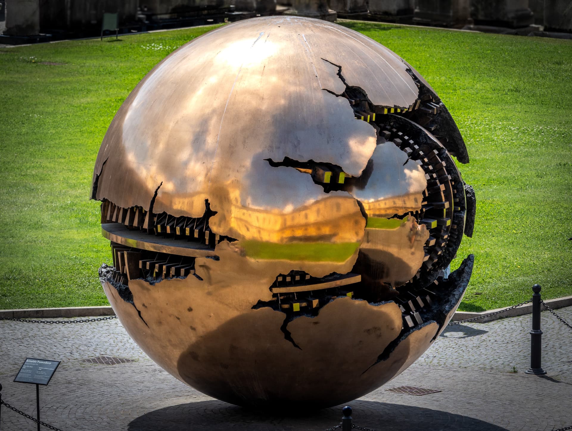 Bronze cracked sphere by Arnaldo Pomodoro reflecting the sky in Rome