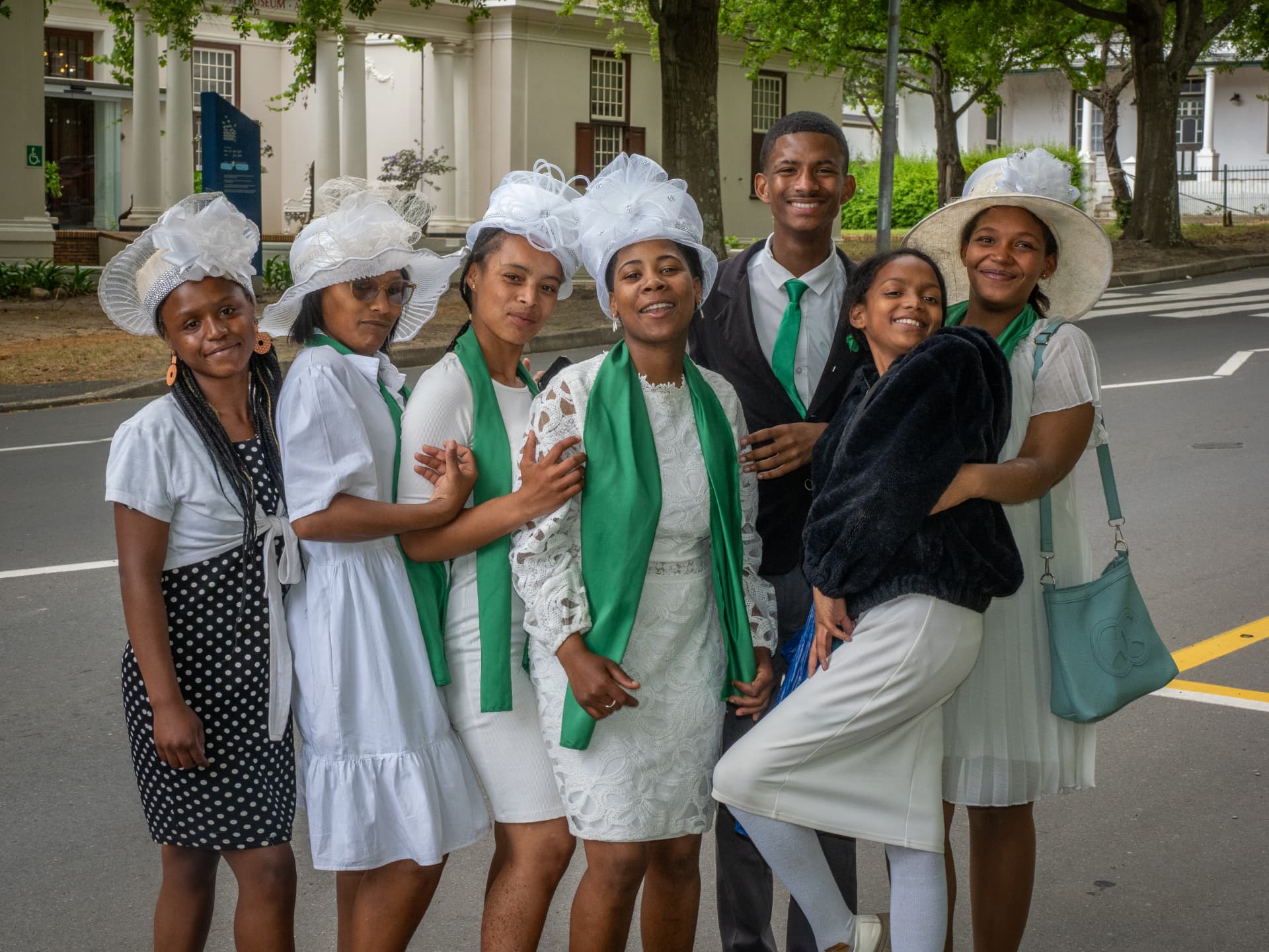 Churchgoers in white and green celebrating together outside a colonial church